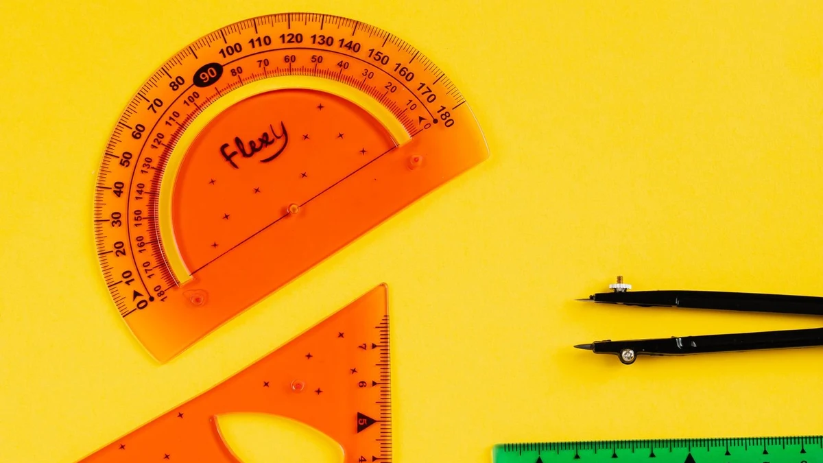 Geometry tools and maths instruments on a desk as a student compares two entrance exam syllabi